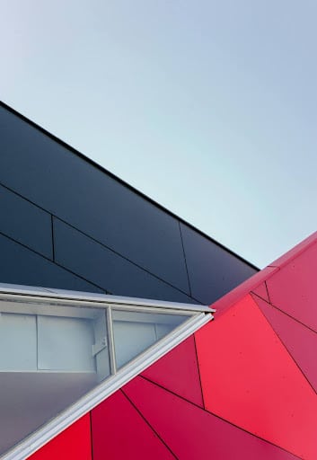 A commercial building with blue and red spandrel glass panels on its roofings.