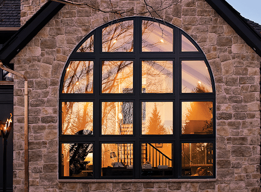 An image of a traditional home’s large luxury glass curved radius window that keeps the interior warm during cold weather.