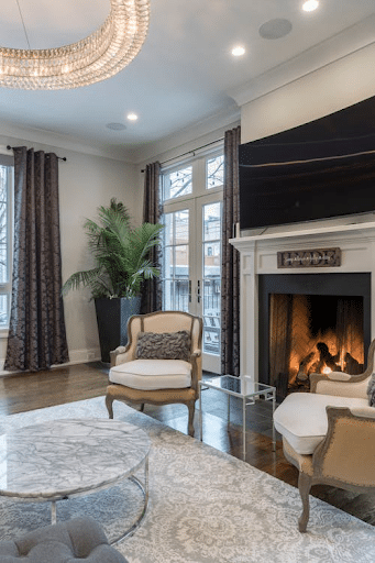 A tempered glass door in a residential living room with the fireplace burning.